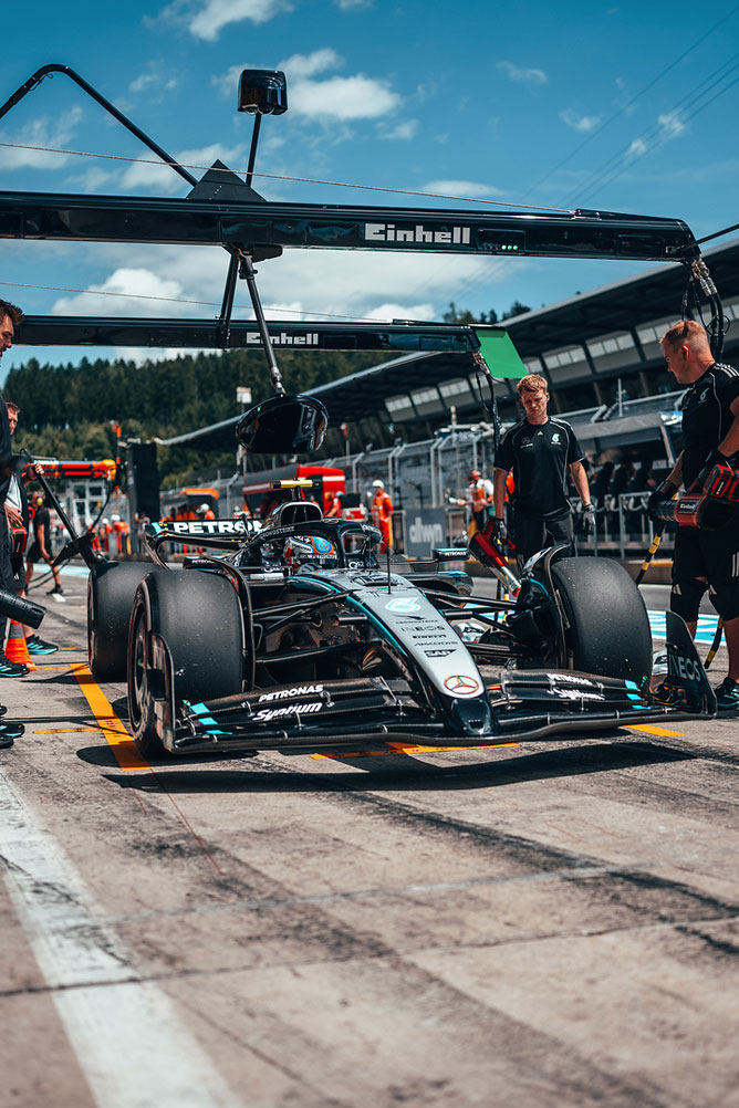 Mercedes-AMG Формула 1 кола е на питлейна, заобиколена от членове на отбора под навес на Einhell.