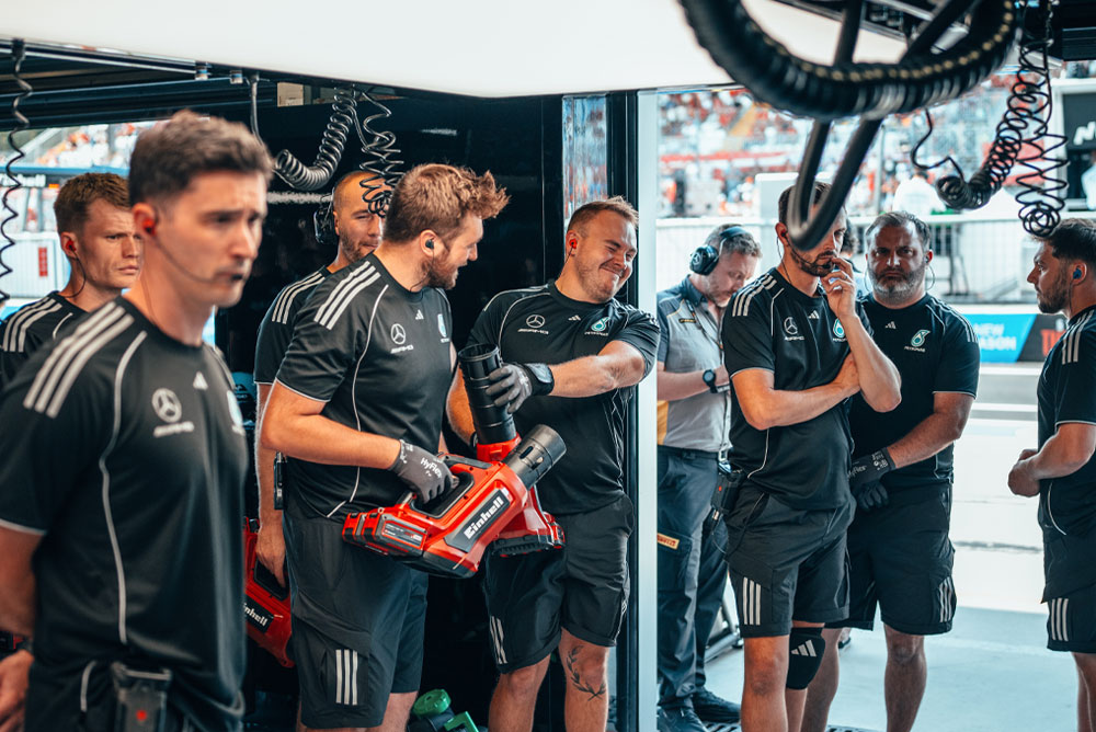 Отборът Mercedes-AMG PETRONAS Formula One Team се намира в гаража. Двама членове на отбора държат червени безжични въздуходувки Einhell и се подготвят за следващото действие.