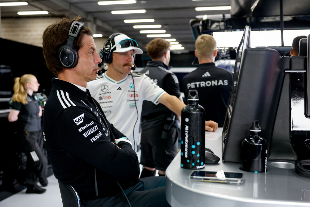 Тото Волф и Валтери Ботас от отбора Mercedes-AMG PETRONAS Formula One Team са заснети на работното място на отбора в гаража. Те са съсредоточени върху състезателната стратегия, наблюдават мониторите и комуникират чрез слушалки.