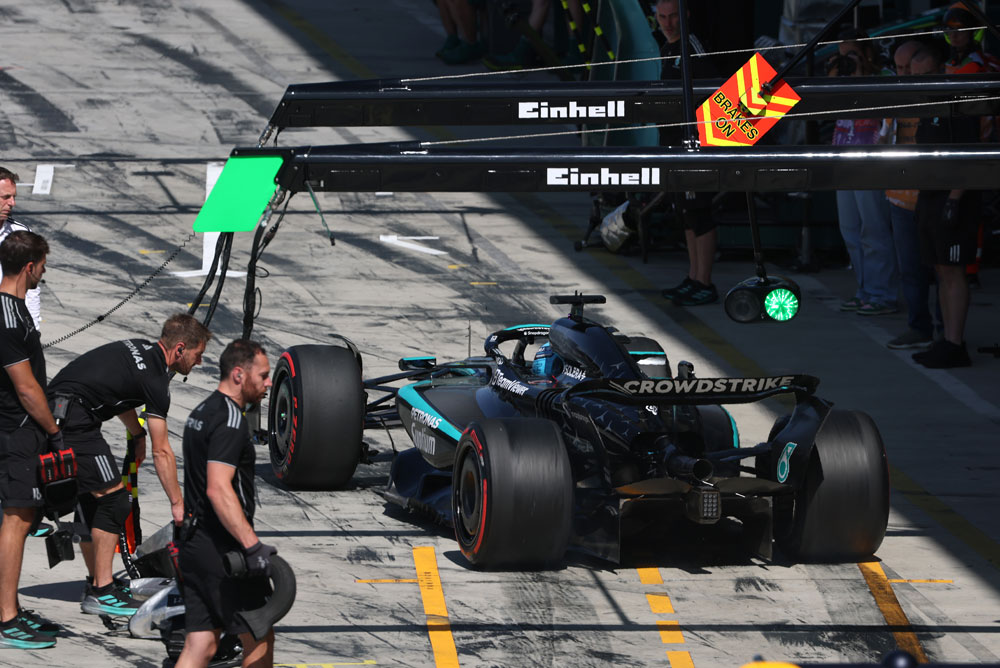 Автомобил на Mercedes-AMG PETRONAS Formula One Team е в питлейна по време на спиране в бокса. Няколко членове на отбора са около автомобила. Логото на Einhell е видимо над боксовата зона.