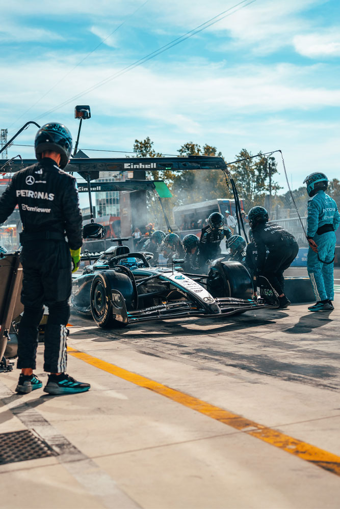 Интензивно спиране в бокса за отбора Mercedes-AMG PETRONAS Formula One Team. Екипът е в действие, сменя гуми и проверява автомобила под портала с марката Einhell.