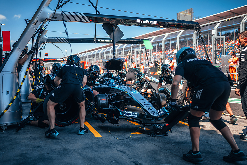 Formula 1 team performing a pit stop on a race car in the pit lane.
