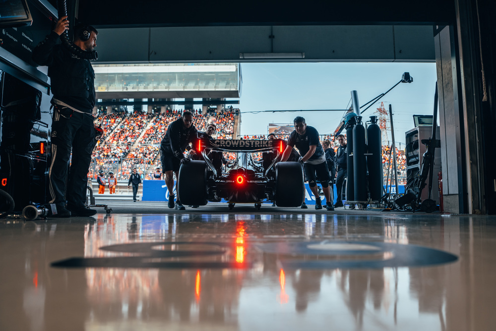 Mercedes F1 car driving past grandstands full of fans