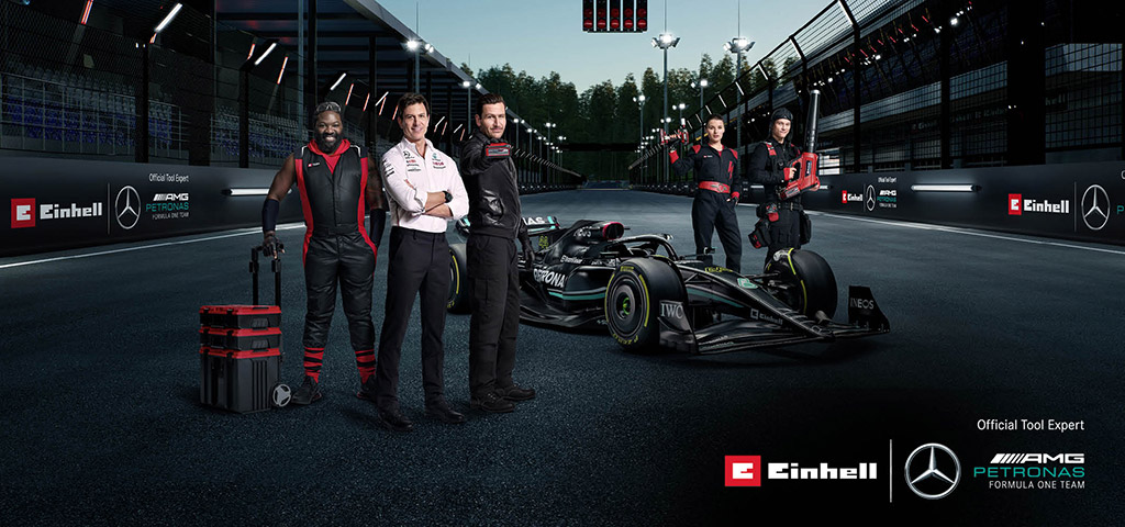 five e team members stand around formula 1 car
