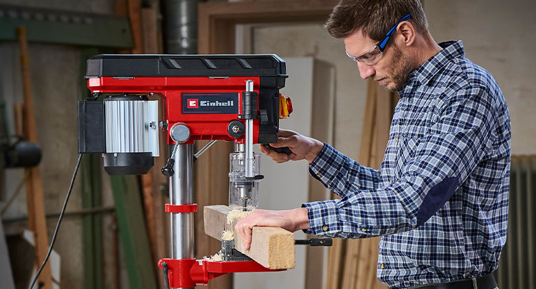 man drilling in a wooden beam